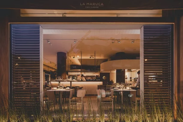 Exterior view of La Maruca de López de Hoyos restaurant in Madrid, showing the interior through large windows.