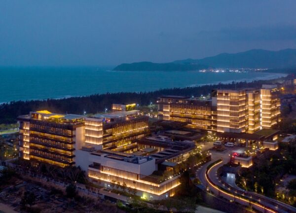 Night view of 1 Hotel Haitang Bay with illuminated façades and tropical landscaping.