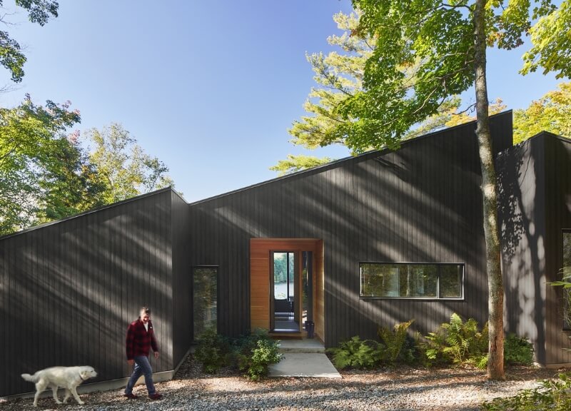 Exterior view of Catchacoma Cottage at its lakeside entrance, surrounded by mature trees.