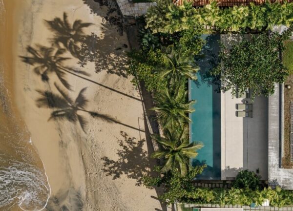 Aerial view of Patios House on the beach, bordered by sea and tropical vegetation.