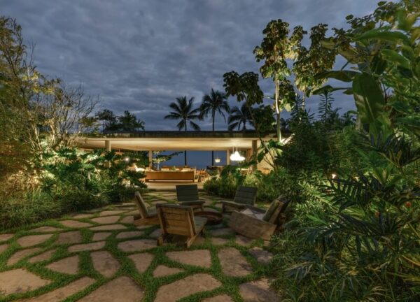 Almost-night view of Patios House’s chill-out area at the back, illuminated against dusk.