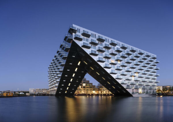 Wide exterior of Sluishuis showing its double cantilever over the IJ, forming a large gateway toward the inner harbour, architectural awards winner.